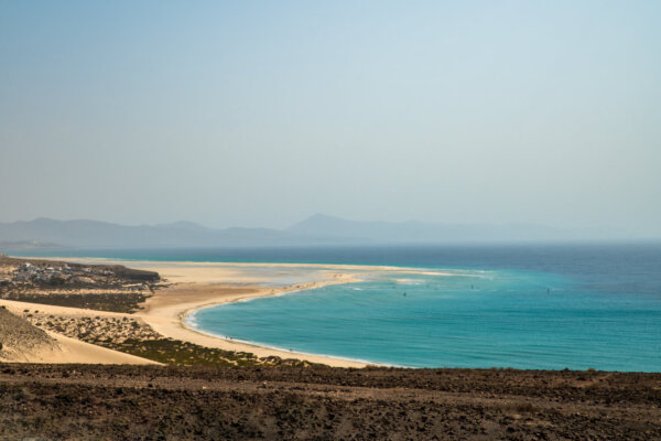 Picturesque view of sandy beach near calm blue sea with mountains on background on summer day